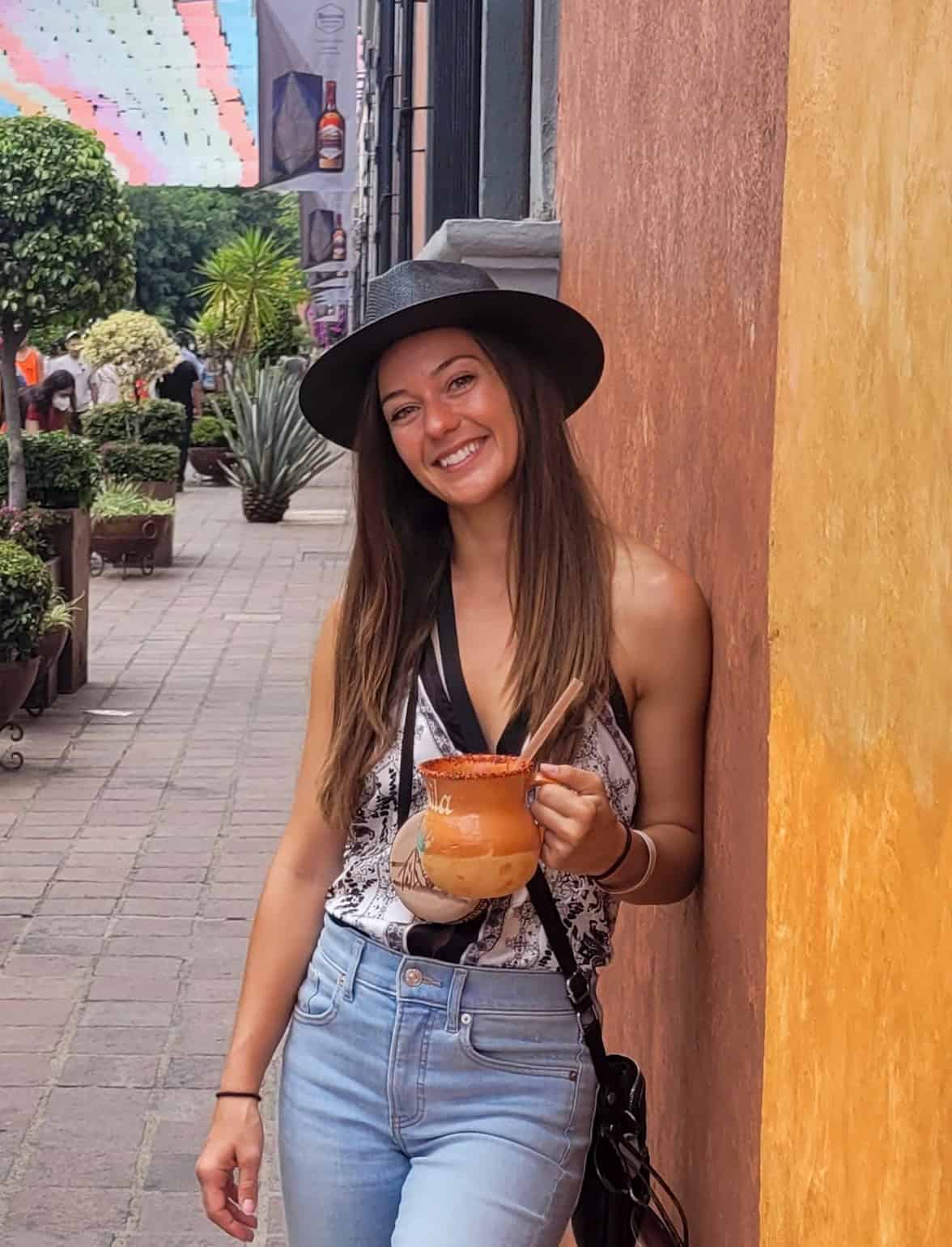 Kait in Tequila, Mexico holding a drink in a traditional clay cup.