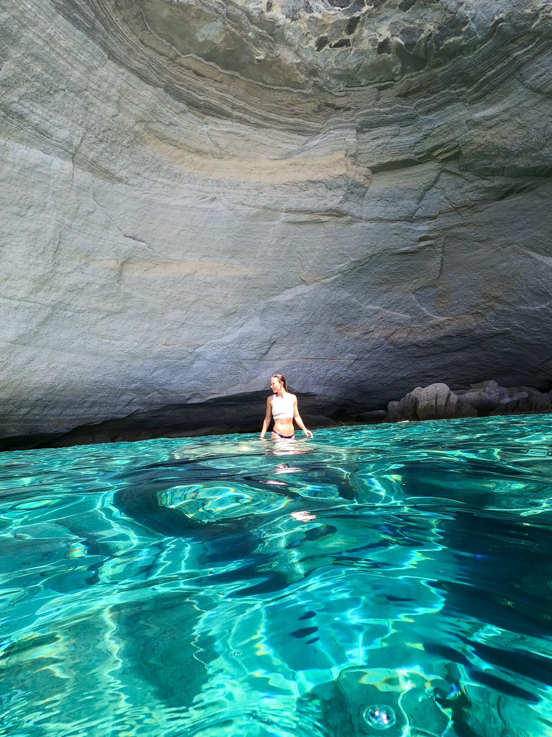 Kait swimming inside the turquoise waters of Kleftiko Caves in Milos, surrounded by dramatic rock formations.