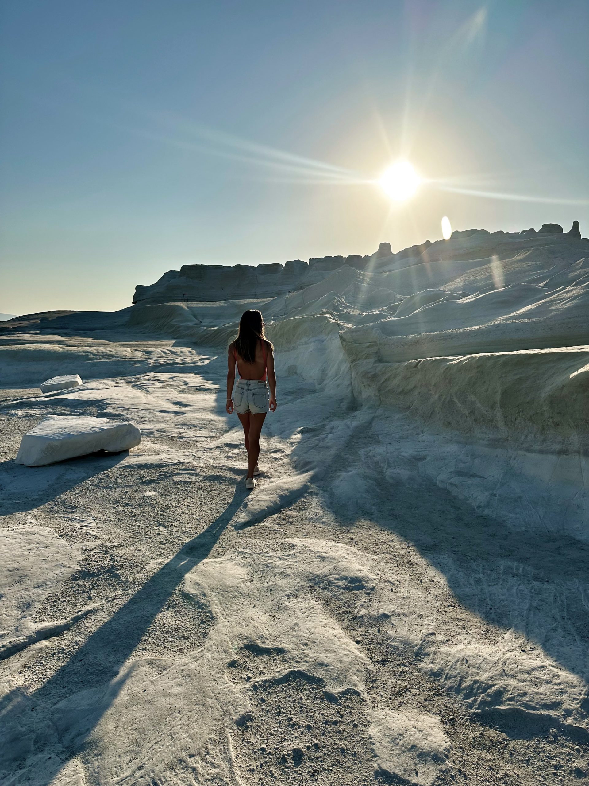 Kait walking across the white volcanic landscape of Sarakiniko Beach in Milos at sunrise.